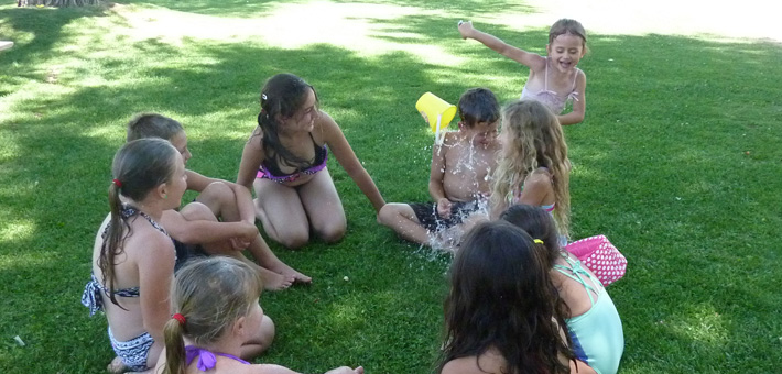 Kids sitting in grass playing a water game